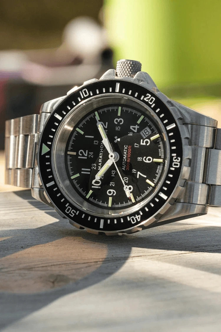 Silver wristwatch with a black dial on a wooden surface