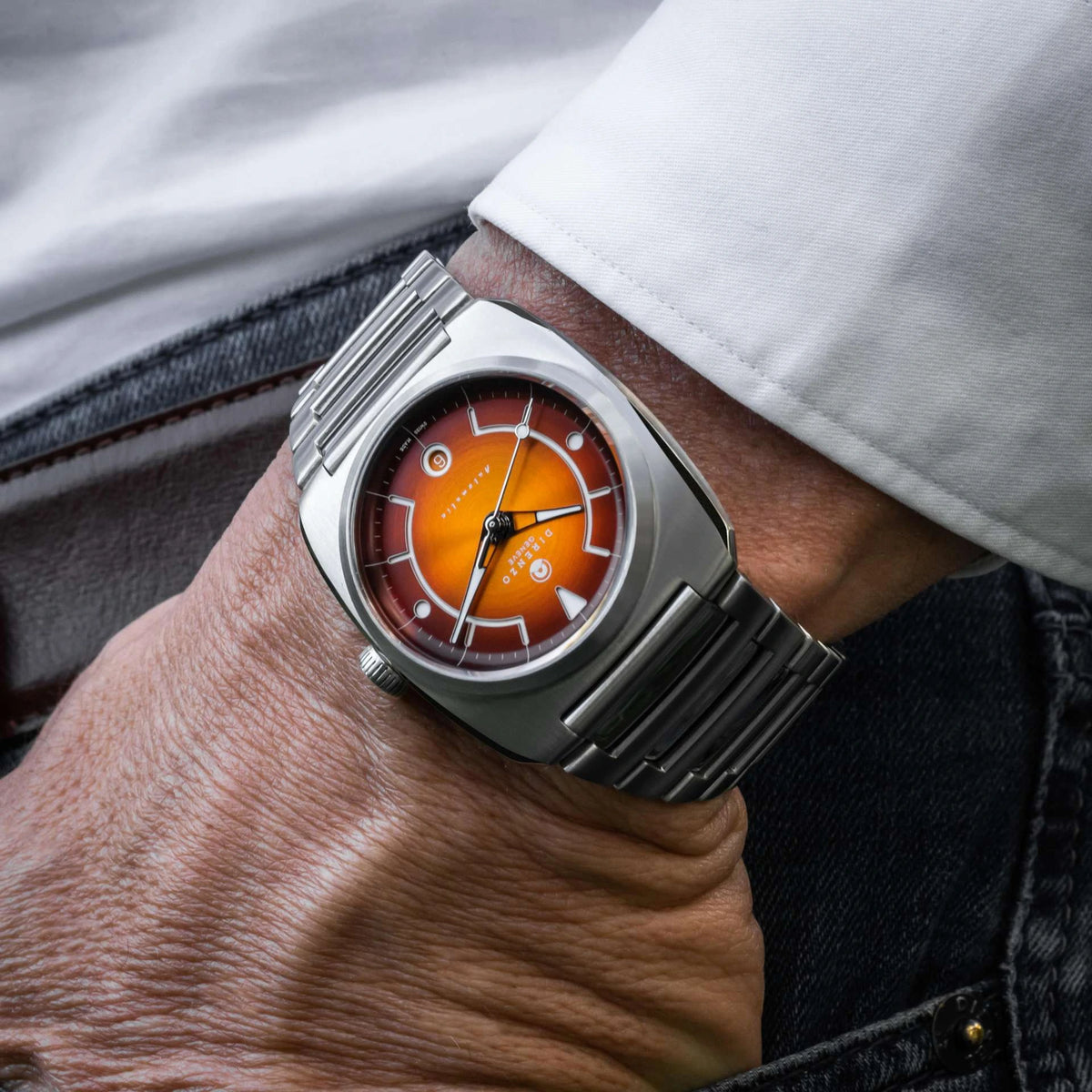 Close-up of a wrist wearing a silver watch with an orange face.
